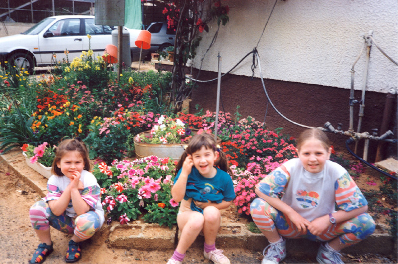 נכדות פרחים על רקע פרחים ליד הבית בחרות. מימין: נוגה, מיכל ויעל הרפז - 1994